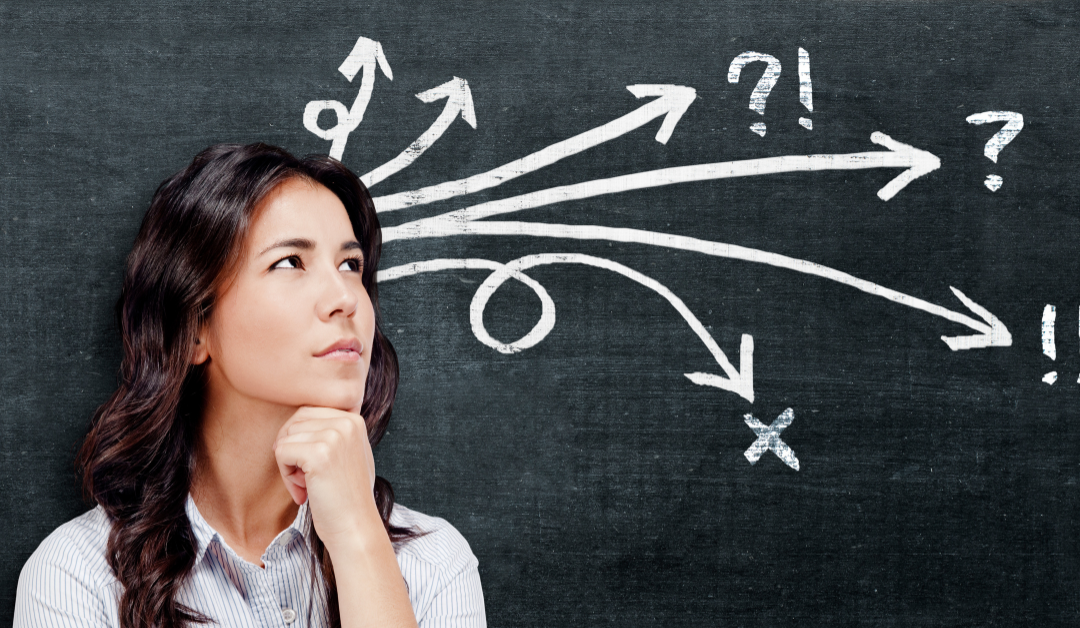 Woman resting her chin on her hand, looking thoughtfully at a chalkboard where arrows branch in many directions toward question marks and exclamation points.
